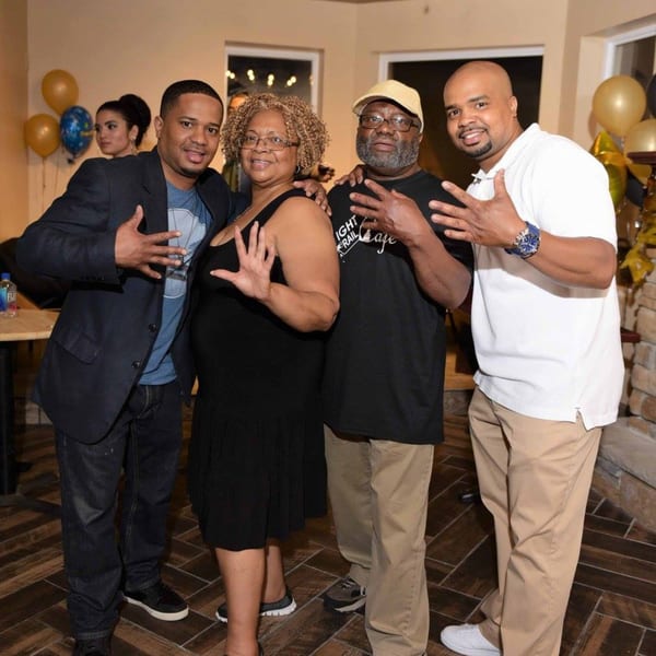 Four adults, two men and two women, smiling and posing with hand gestures at Light Rail Cafe.