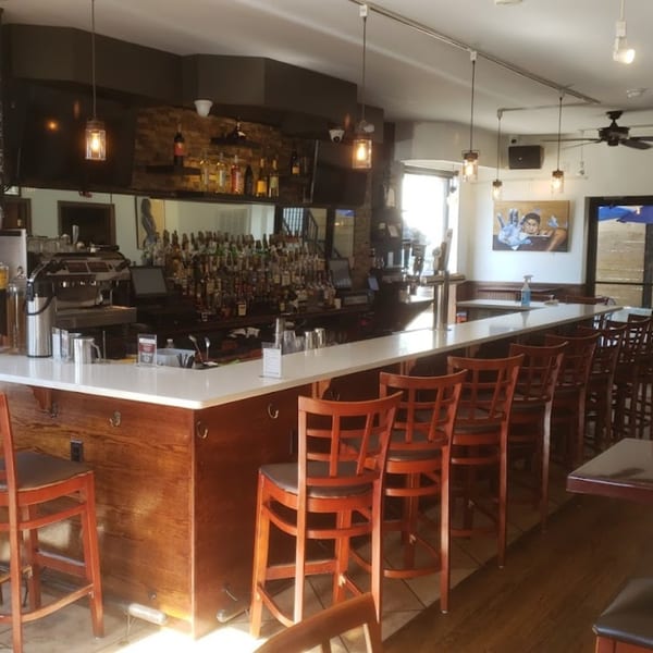 Interior of Light Rail Cafe, featuring a long bar with stools, liquor bottles, and coffee machines.