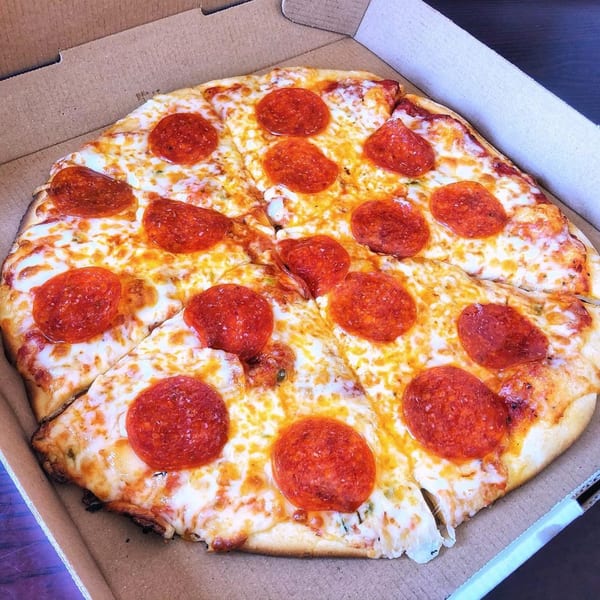 A whole pepperoni pizza with melted cheese and red pepperoni slices in a cardboard box.