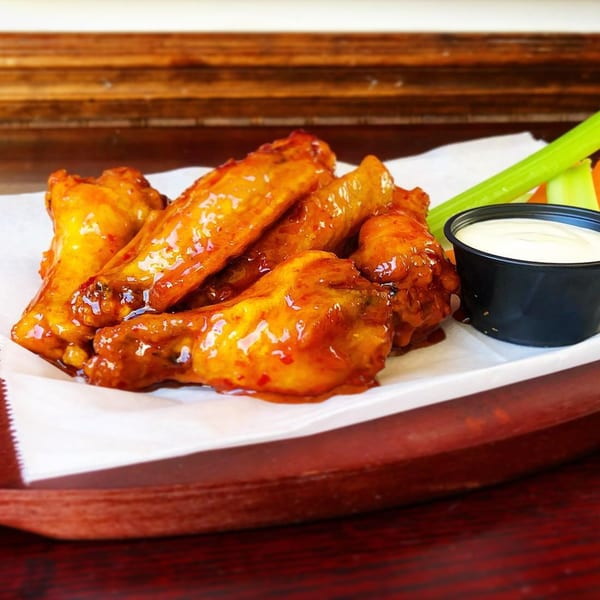 Light Rail Cafe's glazed chicken wings with celery, carrots, and ranch dressing on a white plate.